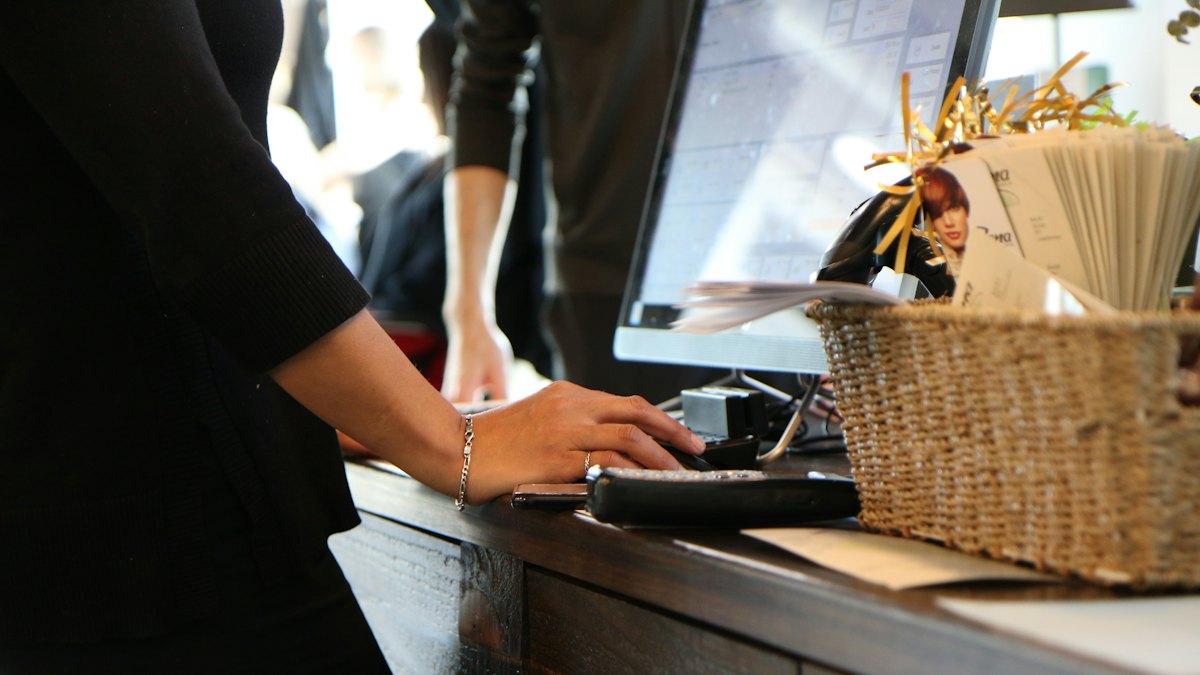 A staff member at a reception desk working on a computer